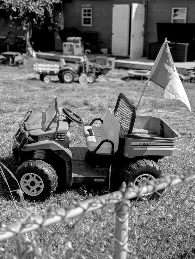 photograph of toy car in a fenced yard