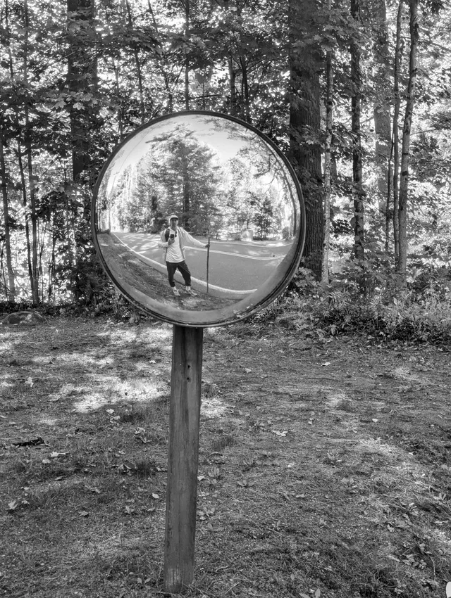 photograph of a refelection of a person in a round mirror